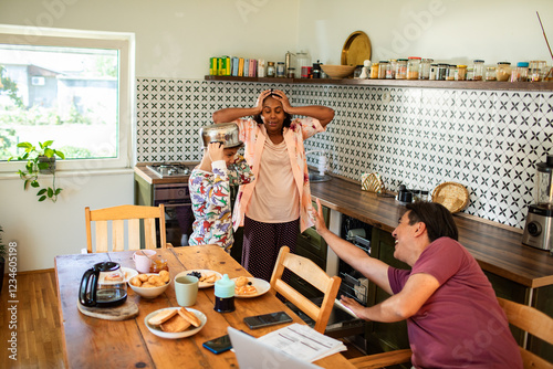 Parents reacting to child wearing pot on head during breakfast in kitchen photo