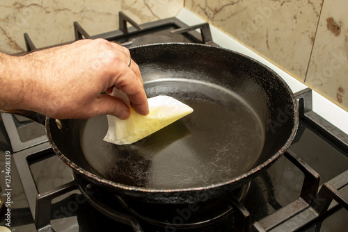 Seasoning a frying pan with vegetable oil and a paper towel, non stick preparation, soft focus close up photo