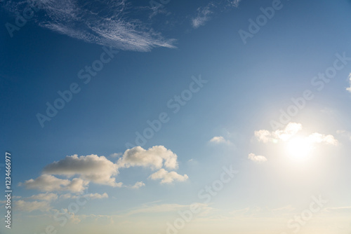 Serene Blue Sky with Soft Clouds Illuminated by Sunshine