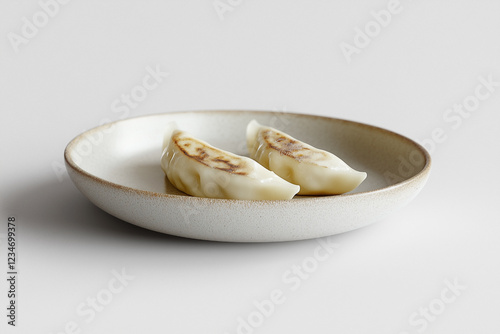 A couple of crispy gyozas with a refreshing green topping served with soy sauce in a small bowl in white background. photo