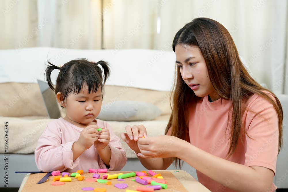 Asian mother takes care of cute daughter, teaching before goes to school. Holding clay, demonstrating shaping techniques. Encouraging creativity, artistic expression, and patience in early learning. Asian mother takes care of cute daughter, teaching before goes to school. Holding clay, demonstrating shaping techniques. Encouraging creativity, artistic expression, and patience in early learning.