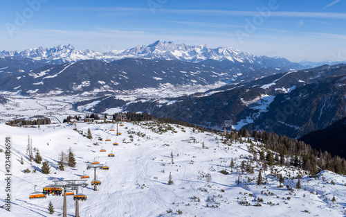 View of skiers on a chair lift and ski slopes in Flachau, Austrian Alps, part of Ski Amade skiing area