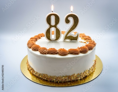 Decorated white cake for birthday or anniversary party, candle number 82, white background photo