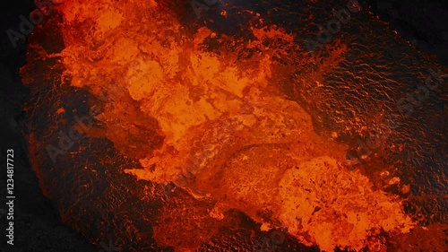 Unique close up view of red hot lava exploding, boiling, and bubbling in the volcano crater, drone shot. Volcanic eruption, natural hazard, and disaster concepts.
