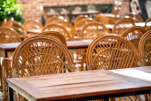 Fotografie Empty wooden tables and wicker chairs on an outdoor patio