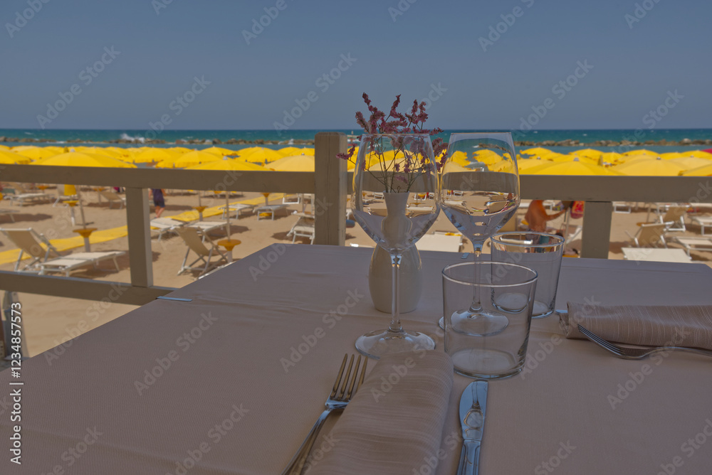 Fototapeta premium glasses with wine for lunch with blurry beach umbrellas in the background
