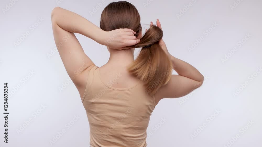 Young beautiful girl in a beige sweater with long hair. The girl combs her hair. Young beautiful girl in a beige sweater with long hair. The girl combs her hair.