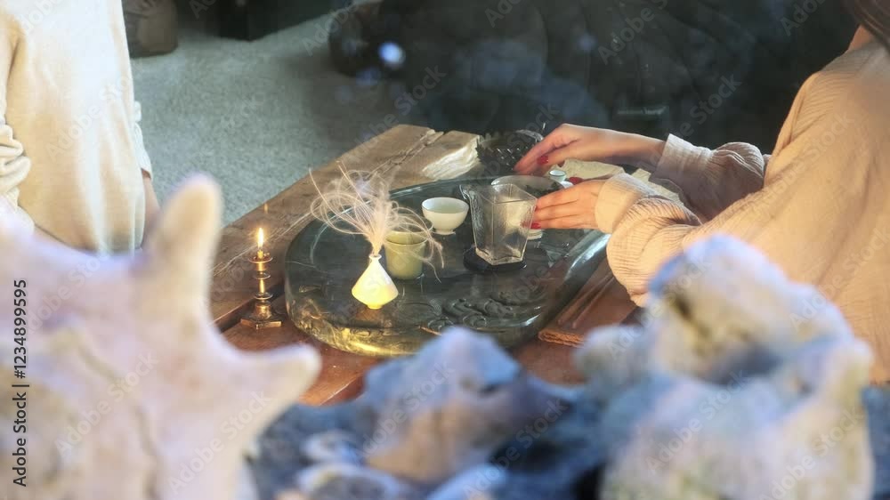 View through an aquarium with fish on a girl conducting a tea ceremony. She pours freshly brewed tea into ceramic cups. The girls drink tea and talk. View through an aquarium with fish on a girl conducting a tea ceremony. She pours freshly brewed tea into ceramic cups. The girls drink tea and talk.