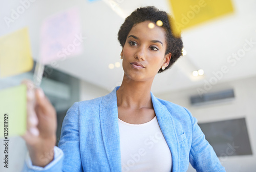Business woman, brainstorming and schedule planning with glass board for tasks, reminder or agenda at office. Female person, analyst or project planner with sticky notes for corporate vision or ideas