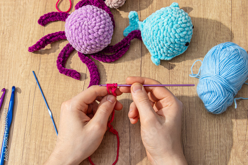 Young man crochets pink yarn. Crocheting amigurumi toys photo