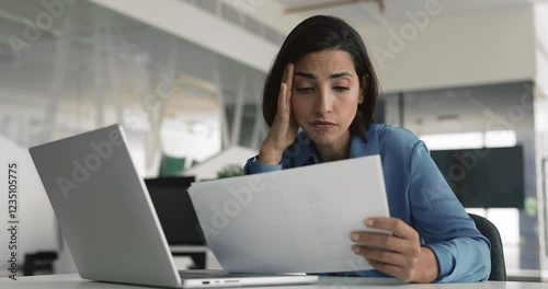 Office employee feels concerned while reads document with negative news, review sales data with revenue decrease, information about demotion, downsizing, or layoffs, unsuccess in work-related matter