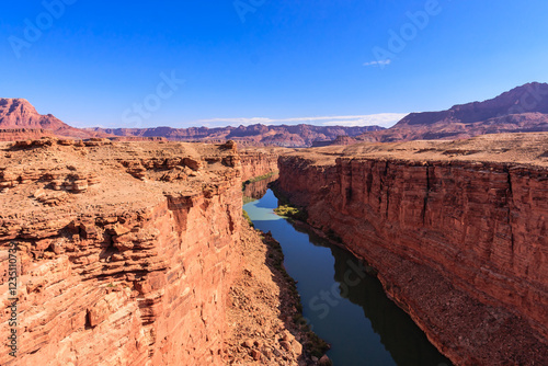 A river runs through a canyon with a clear blue sky above