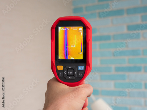 Technician performing thermal imaging inspection, identifying heat loss and potential energy inefficiencies within building wall insulation photo