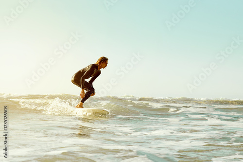 Sea, surfing and blue sky mockup with a man on his surfboard, training or enjoying water sports. Ocean, fitness and surf with a male athlete in a wetsuit for health, wellness or freedom in summer photo