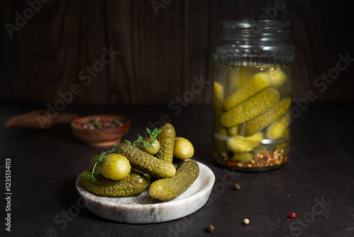 Canvas-taulu Jar and plate filled with pickled cucumbers and gherkins on a black background, fermented food