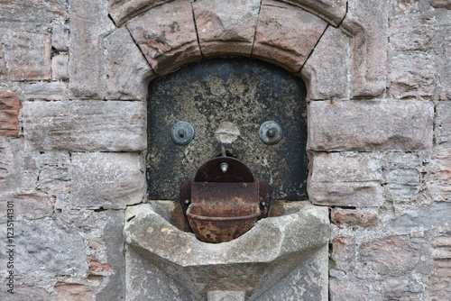 old fountain in stone wall that looks like a face photo