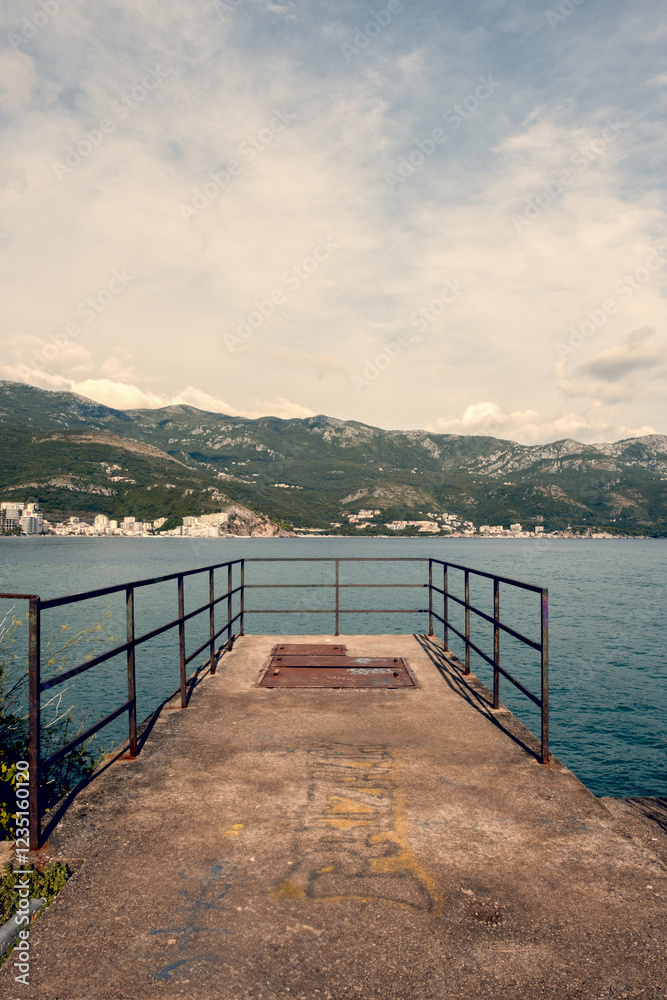 Weathered and abandoned wooden dock stretching into the calm waters of Bečići, Montenegro. A symbol of time's passage and the quiet beauty of decay. Weathered and abandoned wooden dock stretching into the calm waters of Bečići, Montenegro. A symbol of time's passage and the quiet beauty of decay.