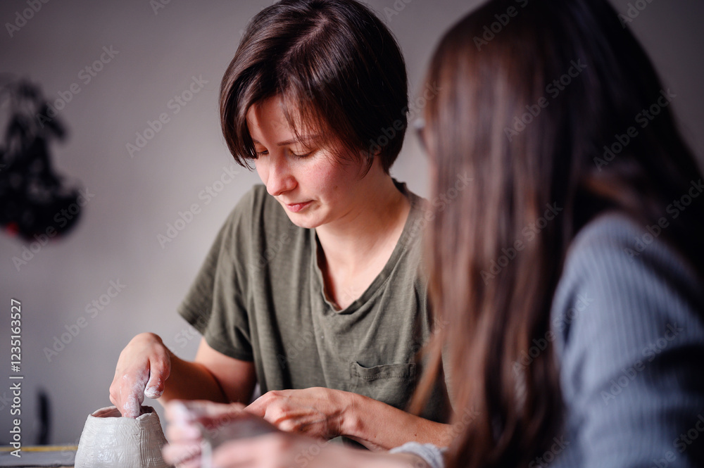 Two women concentrating on a clay sculpting project, working together with focus and creativity. The image captures teamwork and artistic collaboration. Two women concentrating on a clay sculpting project, working together with focus and creativity. The image captures teamwork and artistic collaboration.