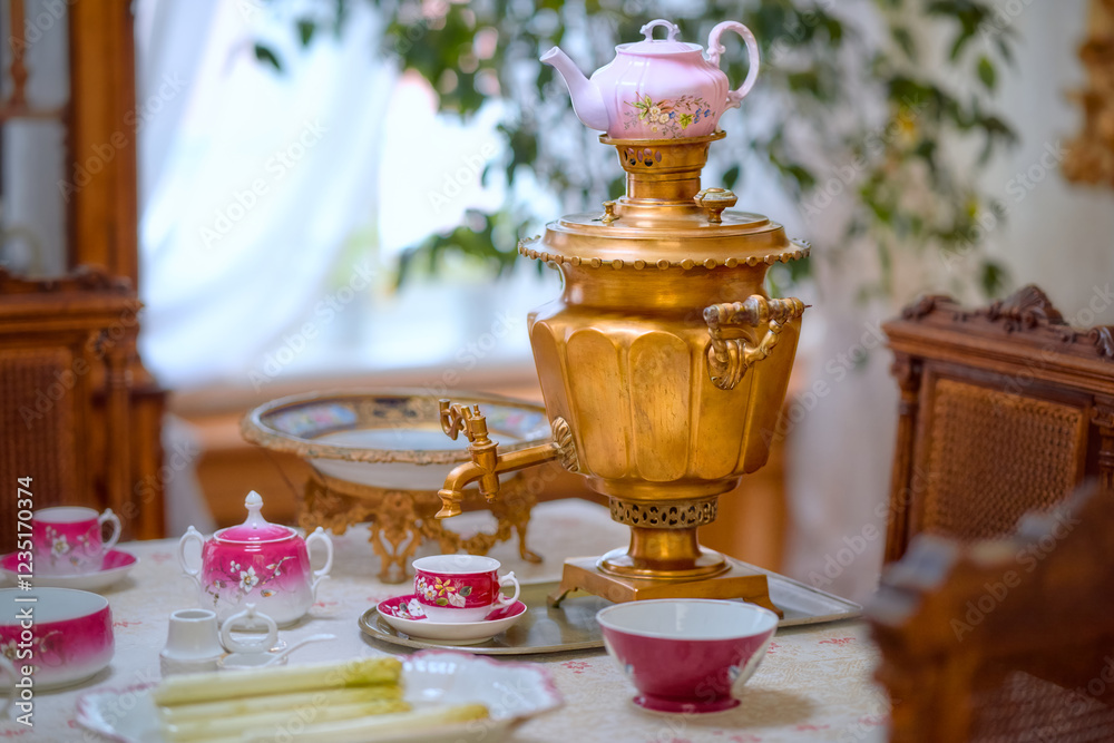 Fototapeta premium Beautiful antique copper samovar on the table in an old hut. Tea accessories on the table by the window.