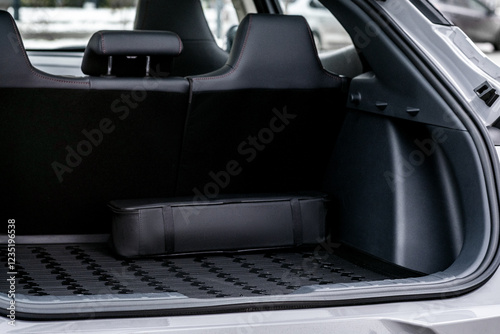 The big black empty trunk of SUV car with rubber mat and a tool box. Open luggage carrier of car closeup