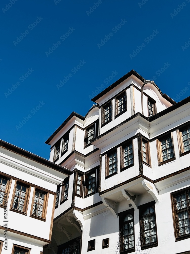 Obraz premium The charming vernacular architecture of Ohrid, with whitewashed buildings and wooden windows, stands out against the vibrant blue sky, showcasing the timeless beauty of this UNESCO-listed town.