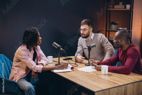 Three radio hosts interviewing a guest in a professional podcast studio, engaging in a discussion and creating audio content photo