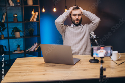 Frustrated podcast host struggling with technical issues during live streaming, hands covering face in stress