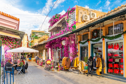 Fototapeta Naklejka Na Ścianę i Meble -  Colorfully decorated shops covered with flowers and sidewalk cafes in the historic Monastiraki district near Plaka in Athens, Greece.