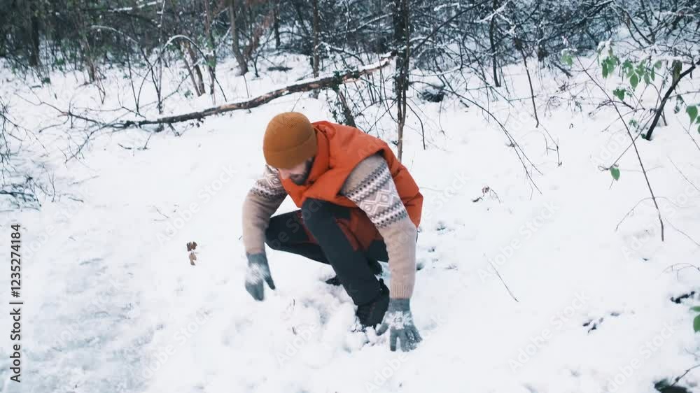 A young Caucasian man throws snowballs while walking in a winter snow forest. Winter outdoor activities concept