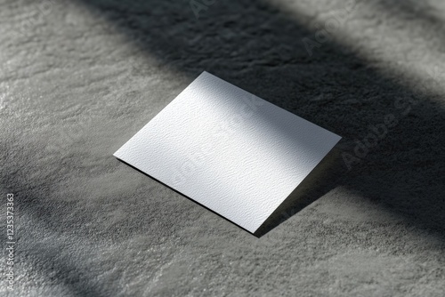 Blank White Card on Textured Surface with Natural Light and Shadow Play photo