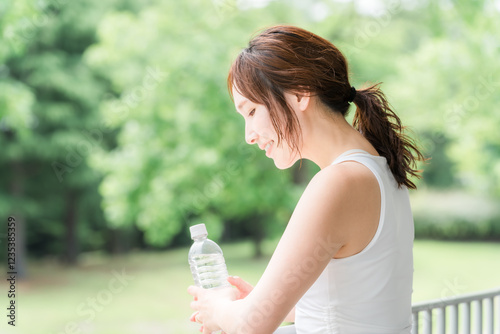 公園・森林の中でミネラルウォーターを飲む若いアジア人女性
 photo