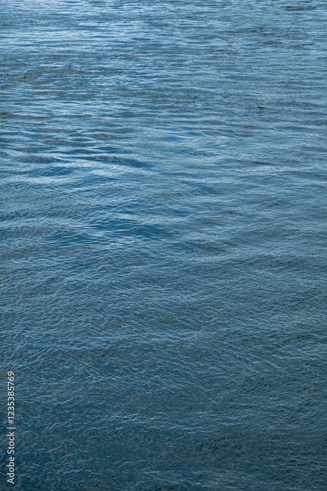 Abstract azure water surface with mild waves, vertical