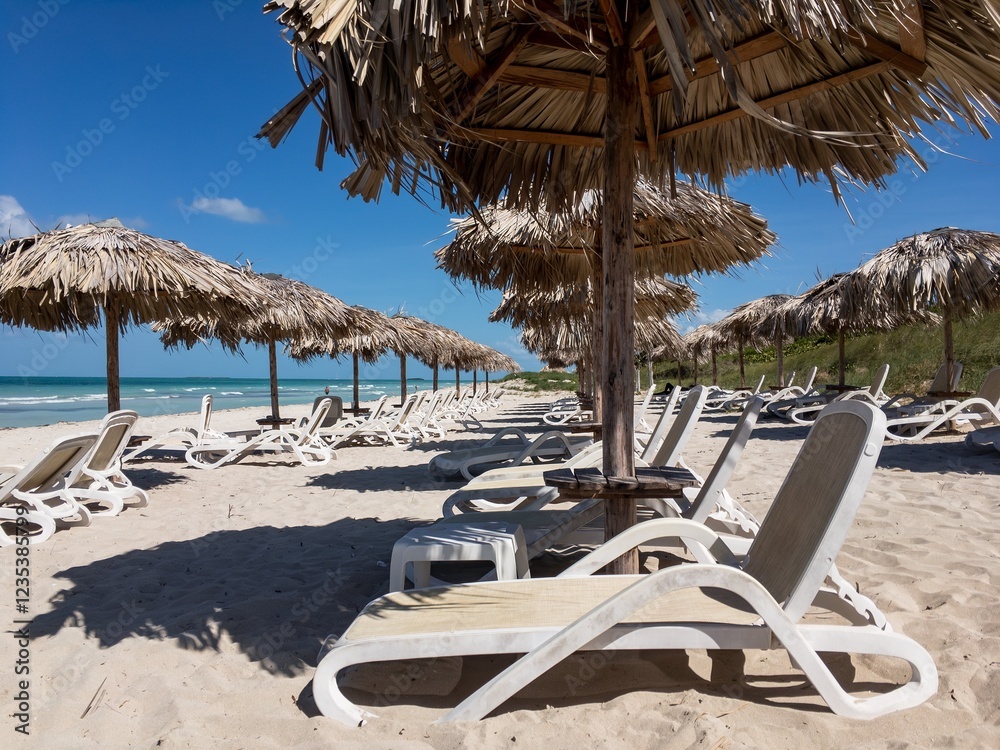 Empty sand beach in Varadero, Cuba. White sunbeds, straw umbrellas and ocean