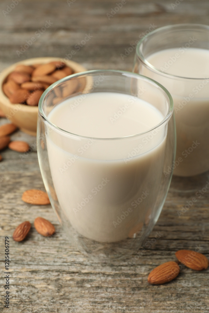 Fresh nut milk in glasses and almonds on wooden table, closeup Fresh nut milk in glasses and almonds on wooden table, closeup