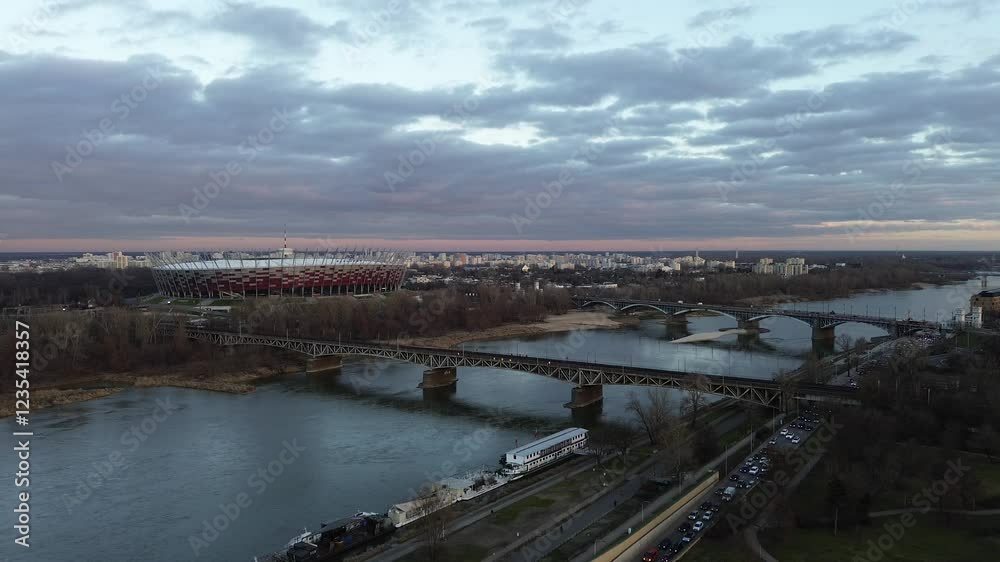 Panoramic view of Warsaw’s riverfront, featuring the PGE Narodowy Stadium, city skyline, and multiple bridges spanning the Vistula River. Panoramic view of Warsaw’s riverfront, featuring the PGE Narodowy Stadium, city skyline, and multiple bridges spanning the Vistula River.