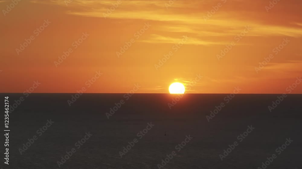 Sunset over the ocean in Oahu, Hawaii, with the sun descending at the horizon. Warm orange and yellow hues fill the sky and reflect on the water. Sunset over the ocean in Oahu, Hawaii, with the sun descending at the horizon. Warm orange and yellow hues fill the sky and reflect on the water.