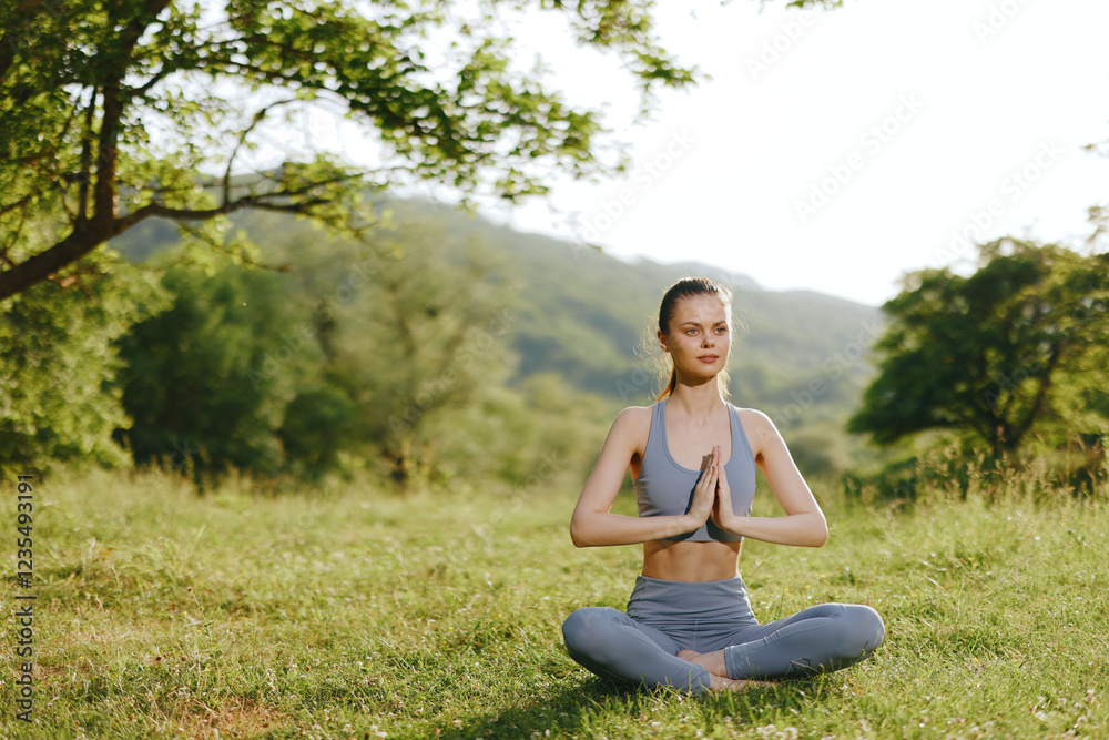 Woman practicing yoga outdoors in a serene green landscape, showcasing tranquility and wellness, dressed in athletic wear with a peaceful expression Woman practicing yoga outdoors in a serene green landscape, showcasing tranquility and wellness, dressed in athletic wear with a peaceful expression