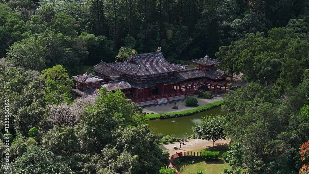Serene aerial view of Byodo In Temple on Oahu Island, Hawaii, with traditional Japanese architecture, red flowering trees, and a tranquil pond. Serene aerial view of Byodo In Temple on Oahu Island, Hawaii, with traditional Japanese architecture, red flowering trees, and a tranquil pond.