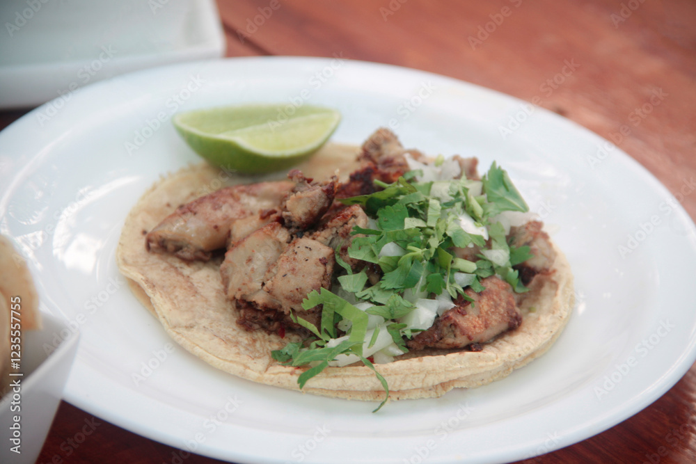 Crispy fried tripe taco on a corn tortilla, garnished with diced white onion, fresh cilantro, and a lime wedge, served on a rustic ceramic plate. Crispy fried tripe taco on a corn tortilla, garnished with diced white onion, fresh cilantro, and a lime wedge, served on a rustic ceramic plate.
