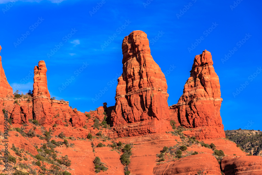 A rocky mountain range with three tall red rock formations A rocky mountain range with three tall red rock formations