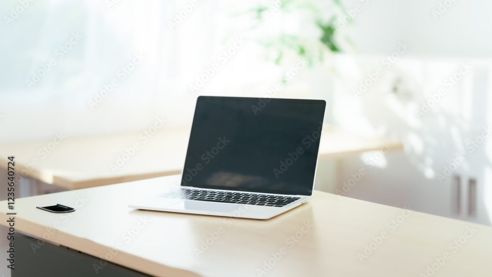 Fototapeta premium Blank white laptop on blank office desk with blurry white background for display your ads.