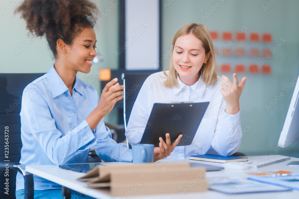 Young African American woman and Russian woman work together in business office, consulting on financial charts using desktop PC and tablet. They discuss strategies and collaborate as colleagues. Young African American woman and Russian woman work together in business office, consulting on financial charts using desktop PC and tablet. They discuss strategies and collaborate as colleagues.