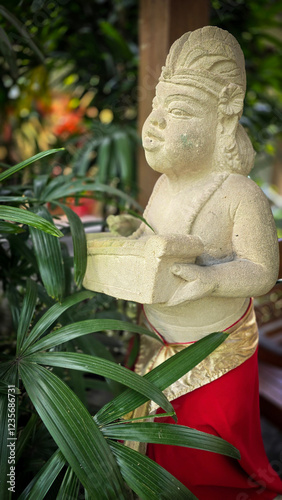 Garden Gnome traditional stone statue situated in a tranquil tropical garden, surrounded by vibrant foliage and artistic decor, harmonizing with the natural beauty of its environment