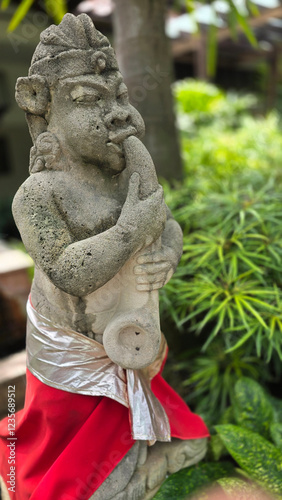 Garden Gnome traditional stone statue situated in a tranquil tropical garden, surrounded by vibrant foliage and artistic decor, harmonizing with the natural beauty of its environment