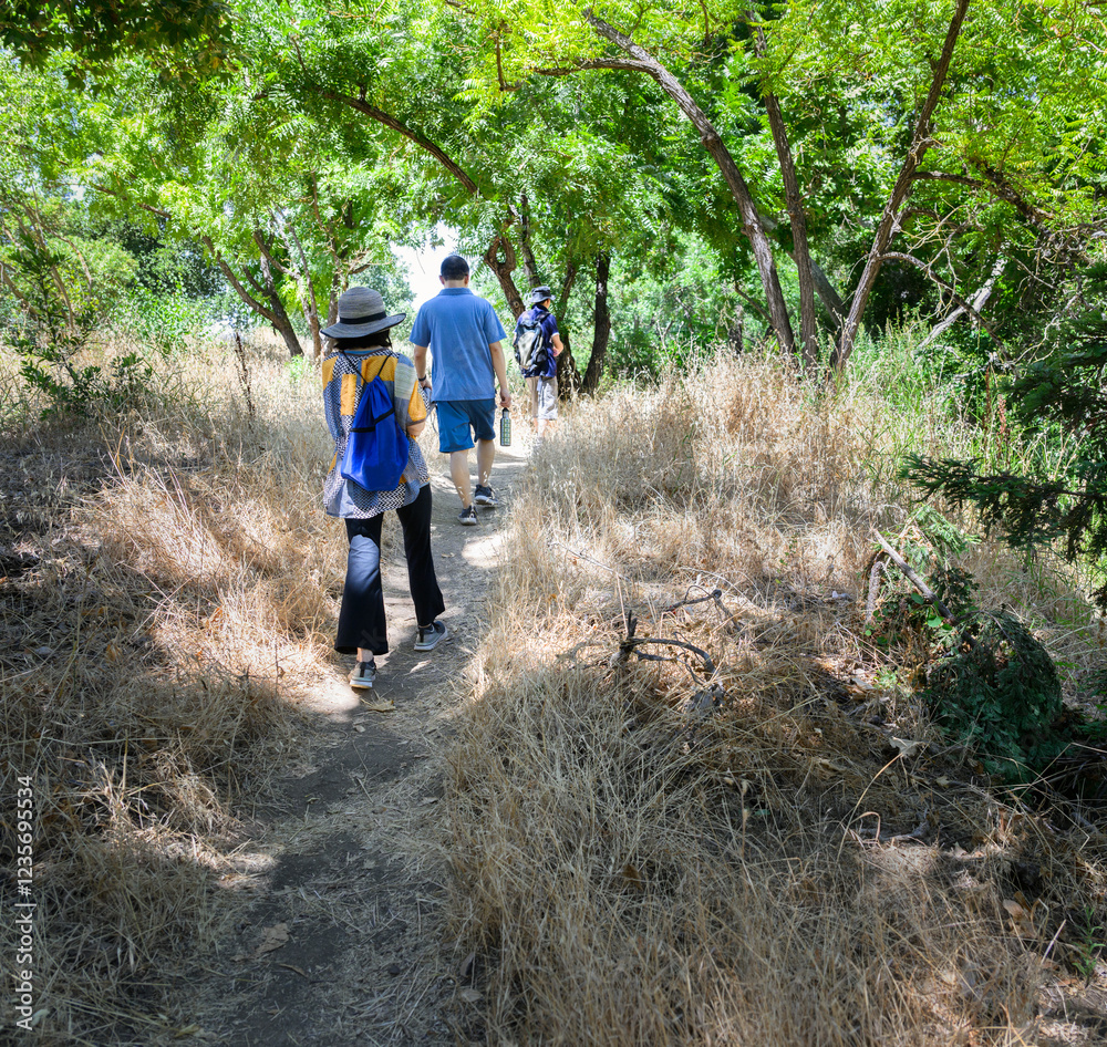 A group of friends walking in the bush. Dried grass along the path. California.