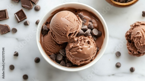 Two scoops of rich, decadent chocolate ice cream, adorned with chocolate chips, in a pristine white bowl. A delectable treat captured from an overhead perspective.