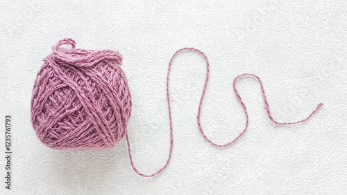 A purple ball of yarn on the table. Unwound yarn of a knitting ball. There is a place for text on the side. Crocheting.