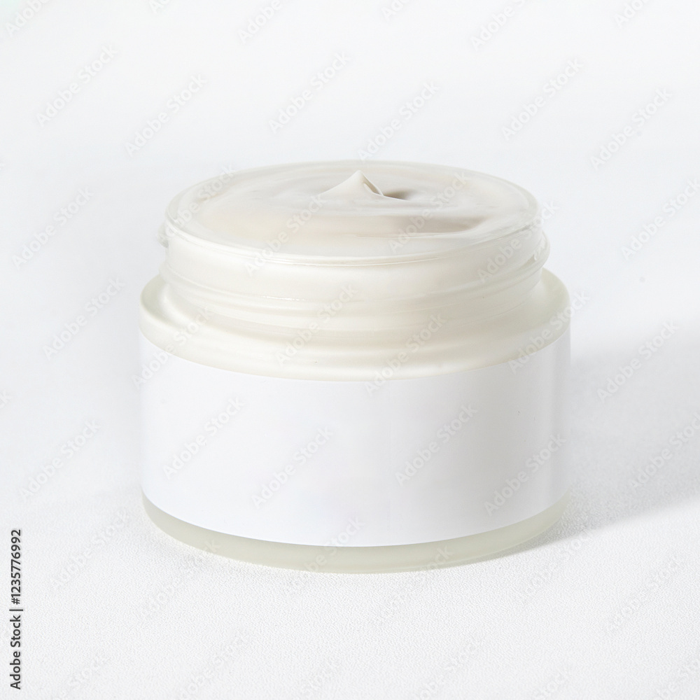 A clear jar containing a rich, creamy moisturizer sits on a neutral backdrop, showcasing its smooth texture and soothing color A clear jar containing a rich, creamy moisturizer sits on a neutral backdrop, showcasing its smooth texture and soothing color