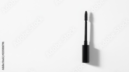 A mascara tube lying flat with its wand resting next to it, displaying the bristles up close. The clean white background ensures the product stands out. photo