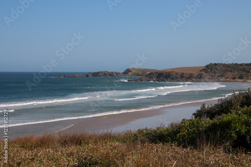 A scenic coastal landscape with rolling waves breaking on a sandy beach